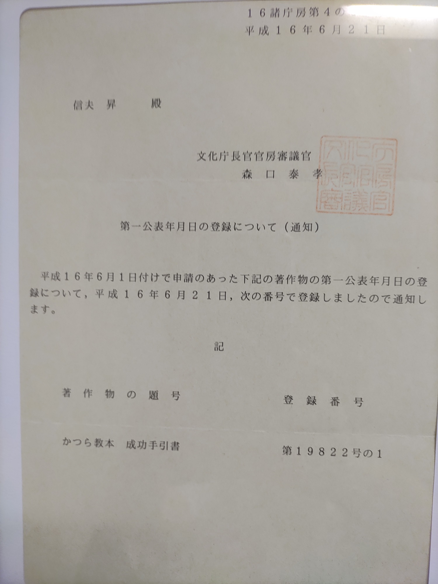 文化庁長官官房審議官名による第一公表年月日の登録通知。著作物の題号かつら教本成功手引書、登録番号第19822号の1